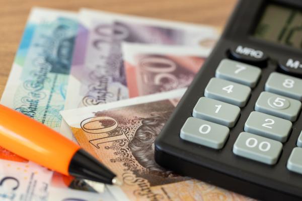 Calculator and yellow pen on top of a UK bank notes